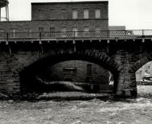View of the East Mill, showing the exterior walls of uncoursed limestone blocks, 1972.; Agence Parcs Canada / Parks Canada Agency, 1972.