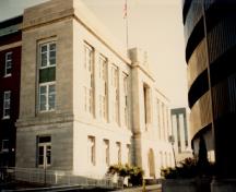 General view of the Federal Building, showing the façade and part of the side finished in light-coloured stone with brick used for the remaining side, 1988.; Public Works Canada / Travaux publics Canada, 1988.