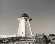 General view of the Light Tower at Point Atkinson, showing the tall hexagonal tower embraced by ribbed buttresses with a generous platform and glazed circular lantern with a large hemisphere cap, 1990.; Canadian Coast Guard / Garde côtière canadienne, 1990.