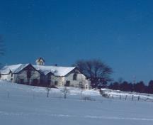 Vue de la façade sud de l'écurie, qui montre la coupole de ventilation centrale avec ses côtés en jalousie, son toit pyramidal et ses pignons miniatures, 1991.; Parks Canada Agency / Agence Parcs Canada, E. Tumark, 1991.