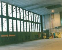 Interior view of the Air Terminal Building (H-7), showing the concrete foundation and floor and the wood framing with steel bracing around the hangar doors.; Transport Canada / Transports Canada