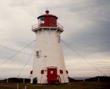 General view of the Light Tower, showing the prominent, multi-sided, red-painted, steel lantern housing and gallery guardrails, 1986.; Transport Canada / Transports Canada, 1986