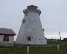 Vue de l'extérieur du phare, qui montre la charpente en lourdes poutres revêtue de bardeaux de bois peintes, 2009.; Parks Canada Agency / Agence Parcs Canada, Jamie Mitchell, 2009.