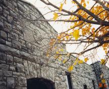 Vue détaillée du bâtiment 24 du CMR, qui montre la très belle exécution du revêtement extérieur en pierre, dont des blocs posés en assises irrégulières, les bossages et les sculptures.; Parks Canada Agency / Agence Parcs Canada.
