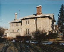 Side view of the Portsmouth Community Correctional Centre, showing shallow hipped roof, wide overhanging eaves, and the large flanking brick chimneys, 1991.; Correctional Service of Canada / Service correctionnel du Canada, 1991.