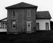 Side view of the Defensible Lockmaster's House, showing the exterior walls constructed of stone masonry and the rear kitchen addition, 1989.; Department of Public Works / Ministère de l'Approvisionnement et des Services, 1989.