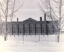General view of the D.V. Currie VC Armoury, showing one of two two-storey wings that house offices, vaults for arms and equipment, classrooms, rifle ranges, and mess rooms, 1989.; Department of National Defence / Ministère de la Défense nationale, 1989.
