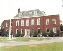 Front elevation of Building 1, showing the symmetry of its massing, in which three flat-roofed wings are set evenly around a central, hipped-roof section, 1990.; Parks Canada Agency / Agence Parcs Canada, 1990.