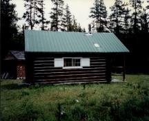 Side elevation of Hoodoo Warden Cabin, showing the wood siding, finished in red-brown paint with light trim, 1997.; Parks Canada Agency / Agence Parcs Canada, 1997.