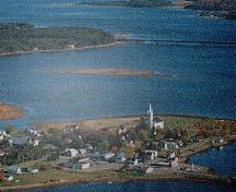 View from the sky, showing the St.Andrew's United Church and cemetery located on a point of land on the Richibucto River.; Village of Rexton