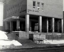 Façade of the Surveys and Mapping Building, showing the open volume of the entrance, recessed behind steel columns that support the office floors above, 1994.; Parks Canada Agency / Agence Parcs Canada, 1994.