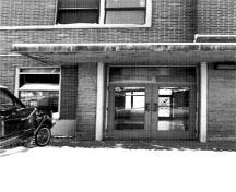 Vue des détails de l'entrée principale de la gare du Canadien National à côté de la tour à escalier, démontrant les portes en bois vitrées à trois panneaux, 1996.; Parks Canada Agency / Agence Parcs Canada, S. D. Bronson, 1996.