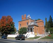 Side view of the McMartin House National Historic Site of Canada showing its two-storey cubic massing under a low pitched hipped roof with lanterns, a cupola and tall side chimneys, 2004.; Parks Canada Agency / Agence Parcs Canada, A. Guindon, 2004.