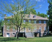 Façade avant de la caserne de Carillonson montrant son plan militaire britannique, d’inspiration classique, et notamment son volume rectangulaire de deux étages sur un soubassement surélevé et ses éléments palladiens, 2003.; Parks Canada Agency / Agence Parcs Canada, E. Le Bel, 2003.