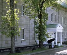 Vue générale du bâtiment 28 (résidence du Gouverneur général), montrant la volumétrie du bâtiment, soit un long bâtiment de maçonnerie de deux étages, formé de sept baies, 1993; Parks Canada Agency/Agence Parcs Canada, C. Rodriguez, 1993.