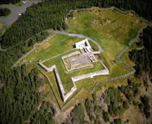 Vue aérienne du lieu national historique du Canada de Castle Hill mettant de l'emphase sur l'emplacement de la forteresse, en haut de la pointe d'une péninsule.; Parks Canada Agency / Agence Parcs Canada, n.d.