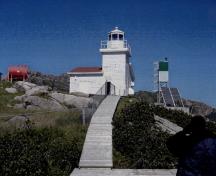 General view of West Point Light Tower, showing its colour pattern, as seen in the use of red shingles on the gable roof and white paint on its metal lantern and railing, 2006.; Fisheries and Oceans / Pêches et Océans Canada, 2006.