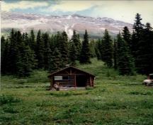View of the main entrance to the Byng Warden Patrol Cabin, showing the log-framed open porch with trussed-purlin supports and posts at the gable end, 1997.; Parks Canada Agency / Agence Parcs Canada, 1997.