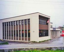 Corner view of the Government of Canada Building showing the flat, cement surfaces without decorative detailing, and the simplicity and abstraction of all components, 1999.; Travaux publics et Services gouvernementaux Canada / Public Works and Government Services Canada, 1999.
