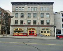 Vue générale de la façade avant de l'école des Arts d'Ottawa montrant les pilastres monumentaux, les fenêtres arrondies et rectangulaires, la maçonnerie qui alterne entre la pierre lisse et la pierre rustiquée et l’épaisse corniche en saillie, 2011.; Agence Parcs Canada / Parks Canada Agency, M. Therrien, 2011.