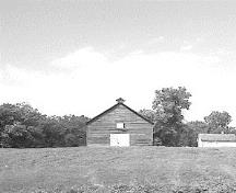 View of the exterior of Fort Dufferin stable, showing its relatively isolated setting within a meadow.; Parks Canada Agency / Agence Parcs Canada.