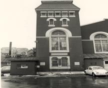 Vue générale d’une des deux tours sur la façade principale du manège militaire de la place Cartier, 1984.; Monique Trépanier, Parks Canada Agency / Agence Parcs Canada, 1984.