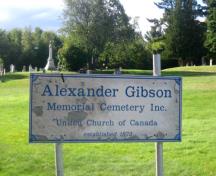 Image of the signage for the Alexander Gibson Memorial Cemetery, with the Gibson Family Plot in the distance; City of Fredericton