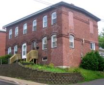 Image of the brick tenement building showing the low-pitched roof and side windows; City of Fredericton