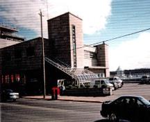 Vue de la façade sud de l'Édifice fédéral qui montre la tour de l'horloge, l'atrium couvert et le garage, 1998.; Parks Canada Agency / Agence Parcs Canada, 1998.