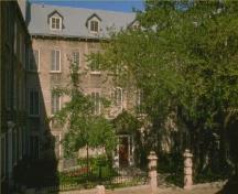 Vue générale la répétition des masses rectangulaires de cinq étages aux fenêtres régulièrement espacées et à l’ornementation réduite.; Agence Parcs Canada / Parks Canada Agency.