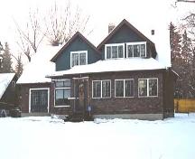 This view of the Wells Residence, from the southeast illustrates the front entrance and the Arts and Crafts style influcences with broad overhanging eaves, clinker brick cladding and asymmetrical massing (March 2004).; City of Edmonton, 2004