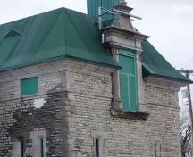 Detail of masonry and Renaissance-style windows breaking the eave line at the second storey.; Source: Andrew Waldron, Parks Canada, 2014.