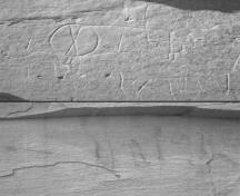 Vue en détail de l’art rupestre à Áísínai'pi qui consiste en des gravures (pétroglyphes) sur le dessus et des peintures (pictogrammes) sur le fond, 2002.; Parks Canada Agency/ Agence Parks Canada, 2002.