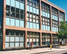 General view of the Government of Canada Building, showing the inset curtain wall of blue spandrel panels and the green tinted glazing, 1996.; Parks Canada Agency | Agence Parcs Canada, 1996.