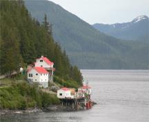 General view of Boat Bluff Lighthouse and related buildings showing the setting of the complex surrounded by water and rugged forest of Nothwest Pacific, 2011.; Kraig Anderson - lighthousefriends.com