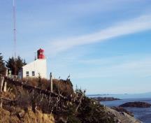 Vue générale du phare de McInnes Island dont la tour est érigée au coin d'un bâtiment rectangulaire; Lise Desmanche