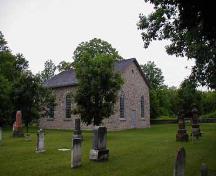 Vue en angle de la vieille église en pierre, montrant des parties du cimetière et du mur, 2006.; Parks Canada Agency / Agence Parcs Canada, 2006.