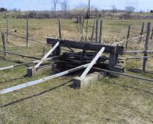 Spider wheel allowing changes of direction of jerker line,with a contemporary derrick in the background, First Commercial Oil Field National Historic Site of Canada, 2005.; Agence Parcs Canada / Parks Canada Agency, A. Roos, 2005.