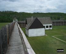 View of building and stockade catwalk inside the fort; Parks Canada / Parcs Canada, 2003