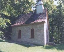 Vue de l'entrée prinicpale de la Chapelle Sainte-Anne, qui montre son volume compact d’un seul étage, sous un toit à deux versants à forte élévation aux larmiers cintrés, 1999.; Parks Canada | Parcs Canada