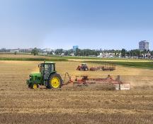 Tracteurs et râteaux dans un champ après la récolte; Agriculture and Agri-Food Canada | Agriculture et Agroalimentaire Canada