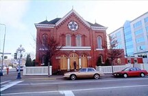 View of the exterior of the Congregation Emanu-el Temple, showing the circular window in the pedimented gable, 1994.; Parks Canada Agency / Agence Parcs Canada, J. Butterill, 1994.