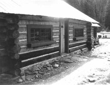 Exterior photograph showing the horizontally laid, peeled round logs with saddle-notched corners.; Parks Canada