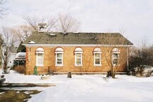Side elevation of the Art Gallery / Former Brougham School House, showing the rectangular brick building capped with a broad, low gable roof and a small bell-tower, 2005.; Parks Canada Agency / Agence Parcs Canada, 2005.