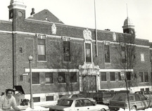 Vue de l'entrée principal du manège militaire, qui montre le caractère de style néoclassique édouardien de la façade, soit l’entrée principale formée par un grand portail en bois et les deux petites tours à dôme en cuivre, 1993.; Department of National Defence / Ministère de la Défense nationale, 1993.