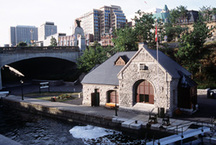 View of the principal entrance of the Lock Office, showing its Romanesque Revival elements, such as thick voussoirs and a large semi-circular arch, 2002.; Parks Canada Agency / Agence Parcs Canada, A. Guindon, 2002.
