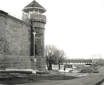 Vue de la tour nord-ouest, qui montre l’enceinte semi-circulaire en béton des postes de gardes, qui donne accès aux chemins de garde qui suivent le sommet du mur d’enceinte, 1990.; Parks Canada Agency / Agence Parcs Canada, Dana Johnson, 1990.