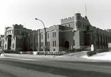 Corner view of the Mewata Armoury, showing one of the four large square, crenelated, three-storey, bastion like corner towers linked by continuous crenelated exterior walls, 1983.; Department of National Defence / Ministère de la Défense nationale, 1983.