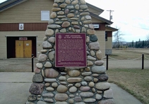 The cairn and HSMBC plaque for Fort Assiniboine NHS. The legion building is behind the cairn.; Parks Canada / Parcs Canada, 1989