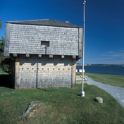 Side view of the St. Andrews Blockhouse, showing its tripartite design with squat lower storey, overhanging upper storey, and pyramidal roof, 2003.; Parks Canada | Parcs Canada, B. Townsend, 2003.